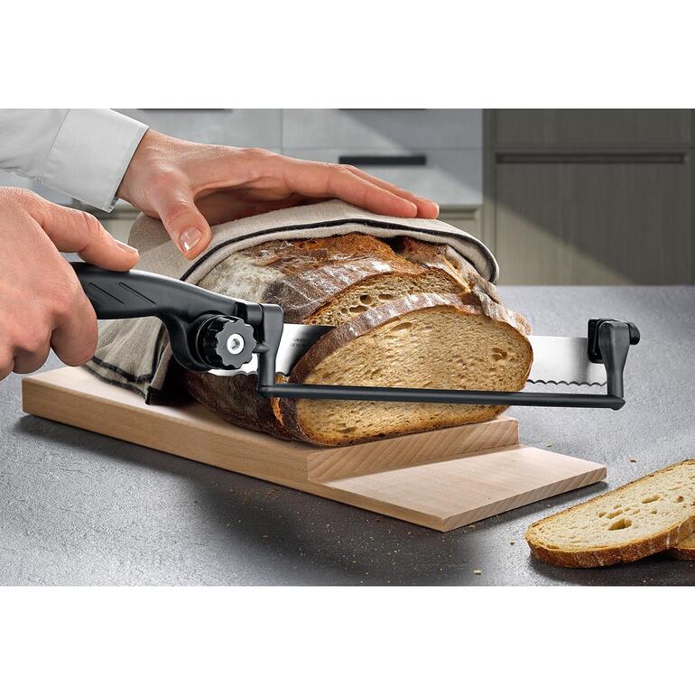 Person schneidet Brot mit einem speziellen Messer auf einem Stufen-Schneidbrett.