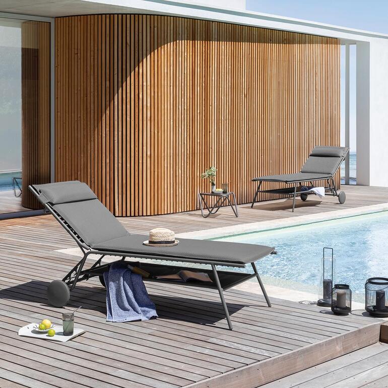 Lafuma Design-Komfortliege am Pool auf Holzdeck mit Sonnenliege im Hintergrund.