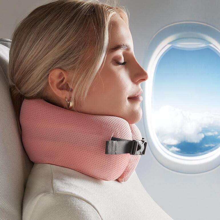Mann mit Komfort-Reisekissen und Kapuze im Flugzeug