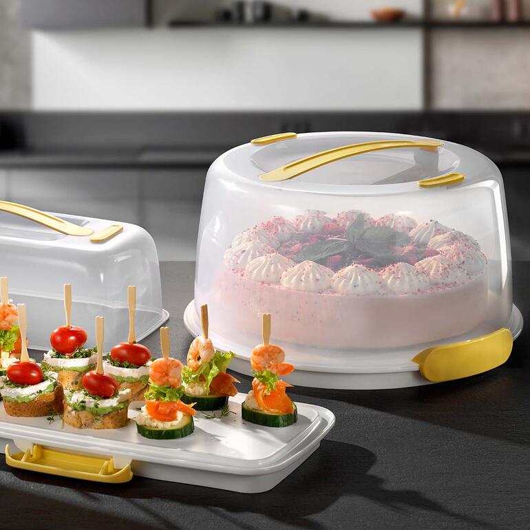 Kühlender Tortenbutler mit Kuchen und Snacks auf einem Tisch.
