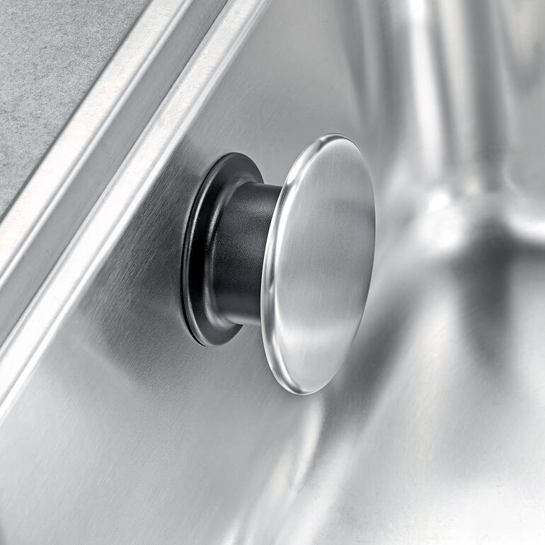 Schnell befestigt: Einfach kurz andrücken, Edelstahlknopf drehen – fertig. Detailansicht des Design-Spültuchhalters mit metallic Oberfläche.