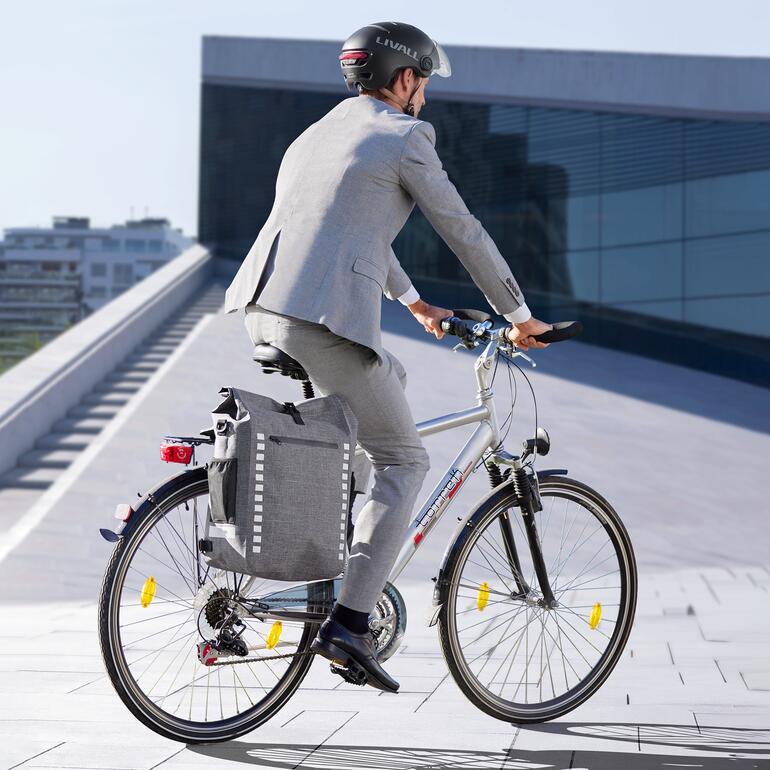 Mann in Anzug fährt auf einem Fahrrad mit einer wasserdichten 4-in-1-Fahrradtasche.