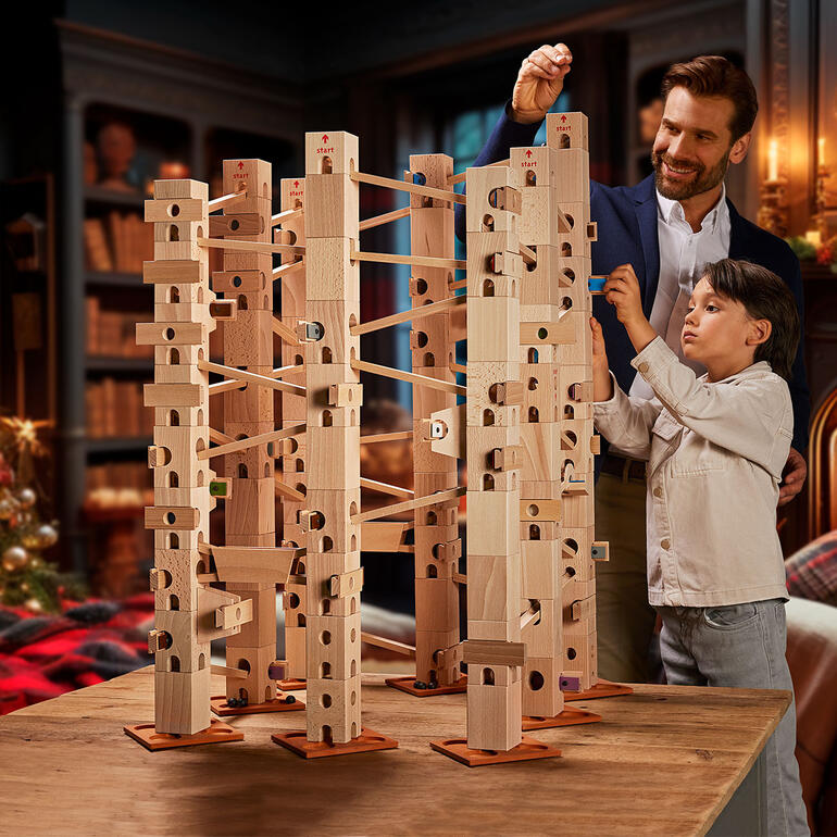 Xyloba Kugelbahn mit Holzbausteinen auf einem Tisch, Kinder und Erwachsene bauen gemeinsam.