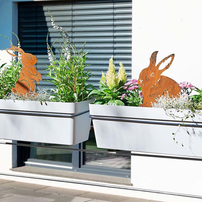 Hasen-Gartenstecker in Blumentöpfen auf einem Balkon dekoriert.