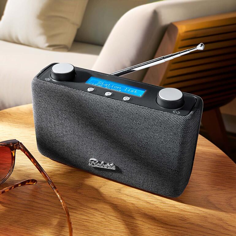 Roberts DAB+ Radio Play 11 auf einem Tisch mit Sonnenbrille.