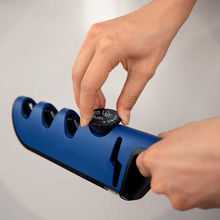 Per Drehregler stellen Sie den individuell benötigten Schleifwinkel ein (Empfehlungen mitgeliefert*). Hand eines Benutzers, die den Schärfer mit einem Drehknopf anpasst