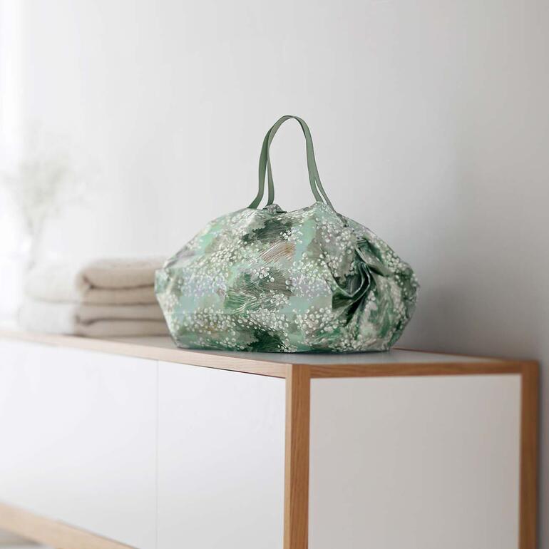 Pop-Up-Tasche auf einem Regal neben gefalteten Handtüchern.
