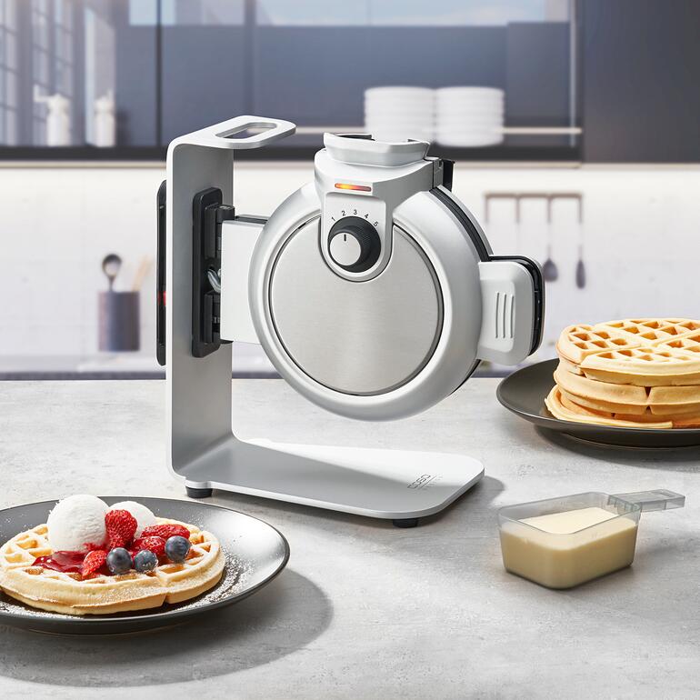 Vertikal-Waffeleisen Waffle Up mit Waffeln und frisch geschlagener Sahne auf dem Tisch.