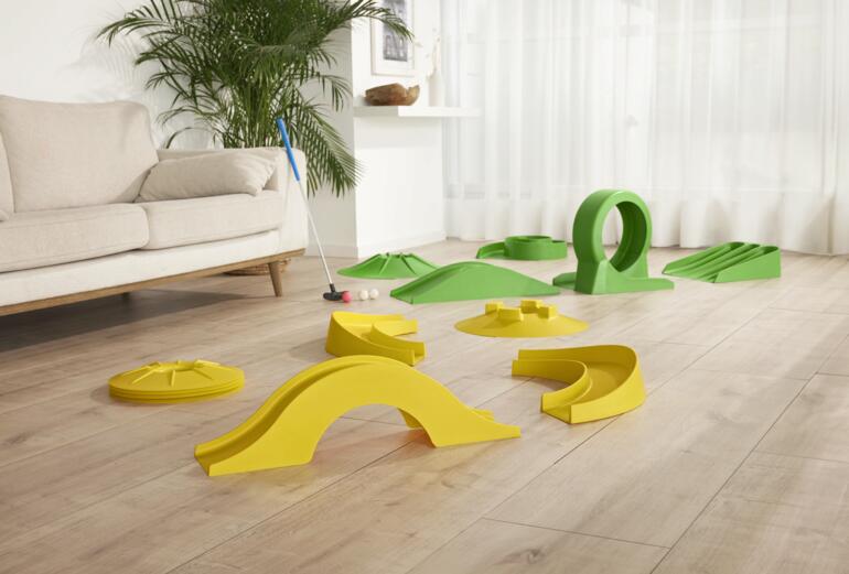 Ein Vergnügen auch drinnen für die ganze Familie, mit Freunden – oder als Pausenspass im Büro. 17-teiliges Minigolf-Set für drinnen, ohne Bahn, auf einem Holzboden.
