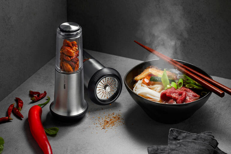 Chili-Schneider X-Plosion® neben einer Schüssel mit dampfendem Essen