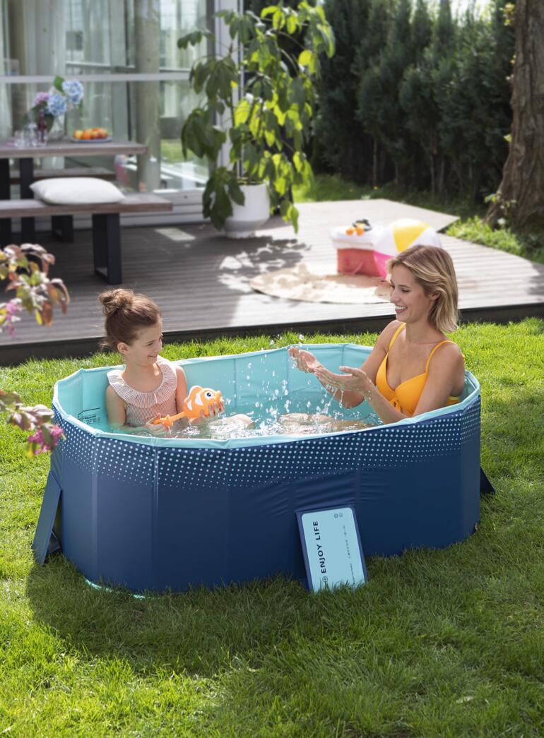 Falt-Pool mit Mutter und Kind im Wasser, umgeben von grüner Rasenfläche.