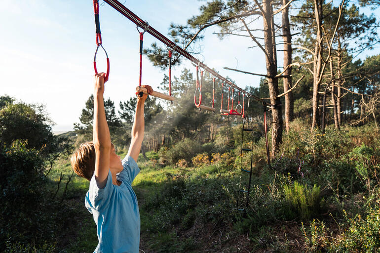 Junge klettert an einem Outdoor-Parcours mit Haltegriffen.