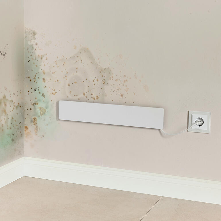 Infrarot-Paneel, an der Wand neben Schimmelflecken sichtbar.