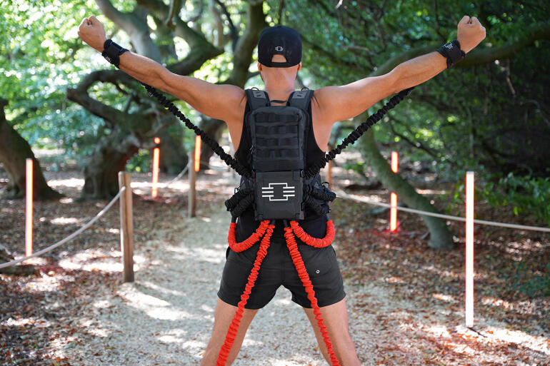 Mann mit Widerstands-Trainingsset, der seine Arme im Freien hebt.