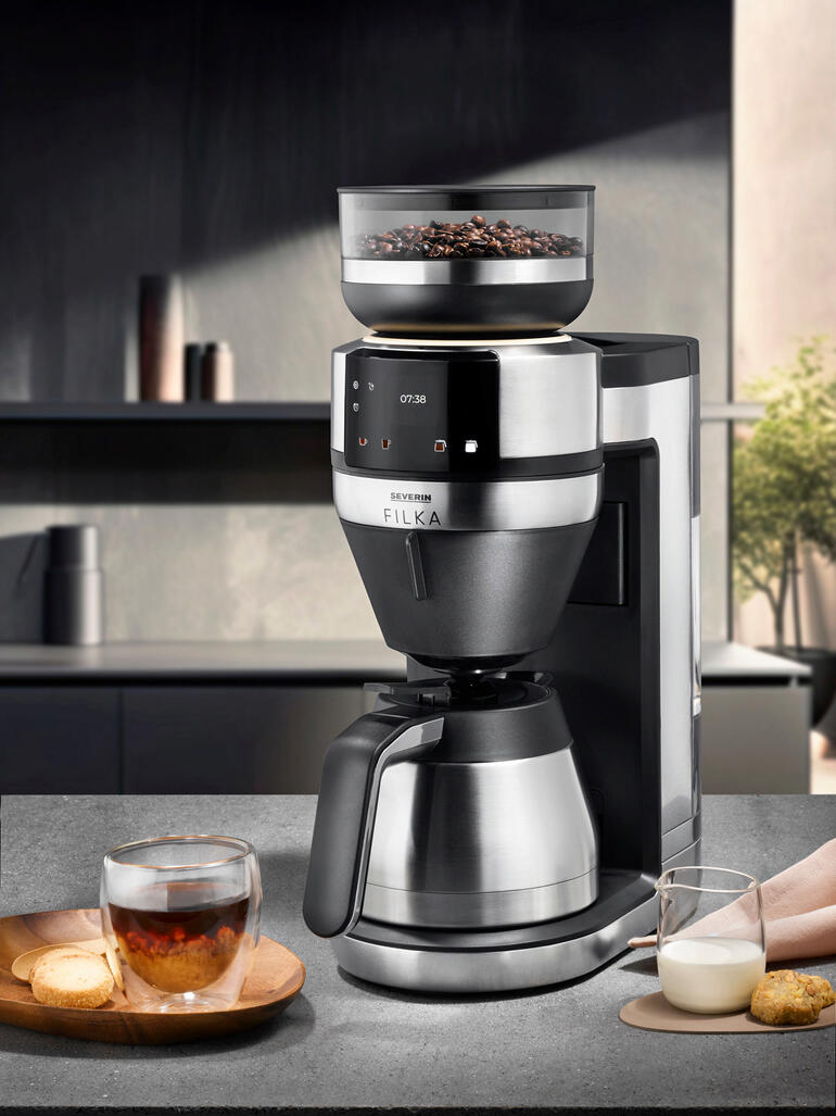 Filterkaffee-Vollautomat FILKA mit einer Kaffeetasse und Milch auf einem Tisch.