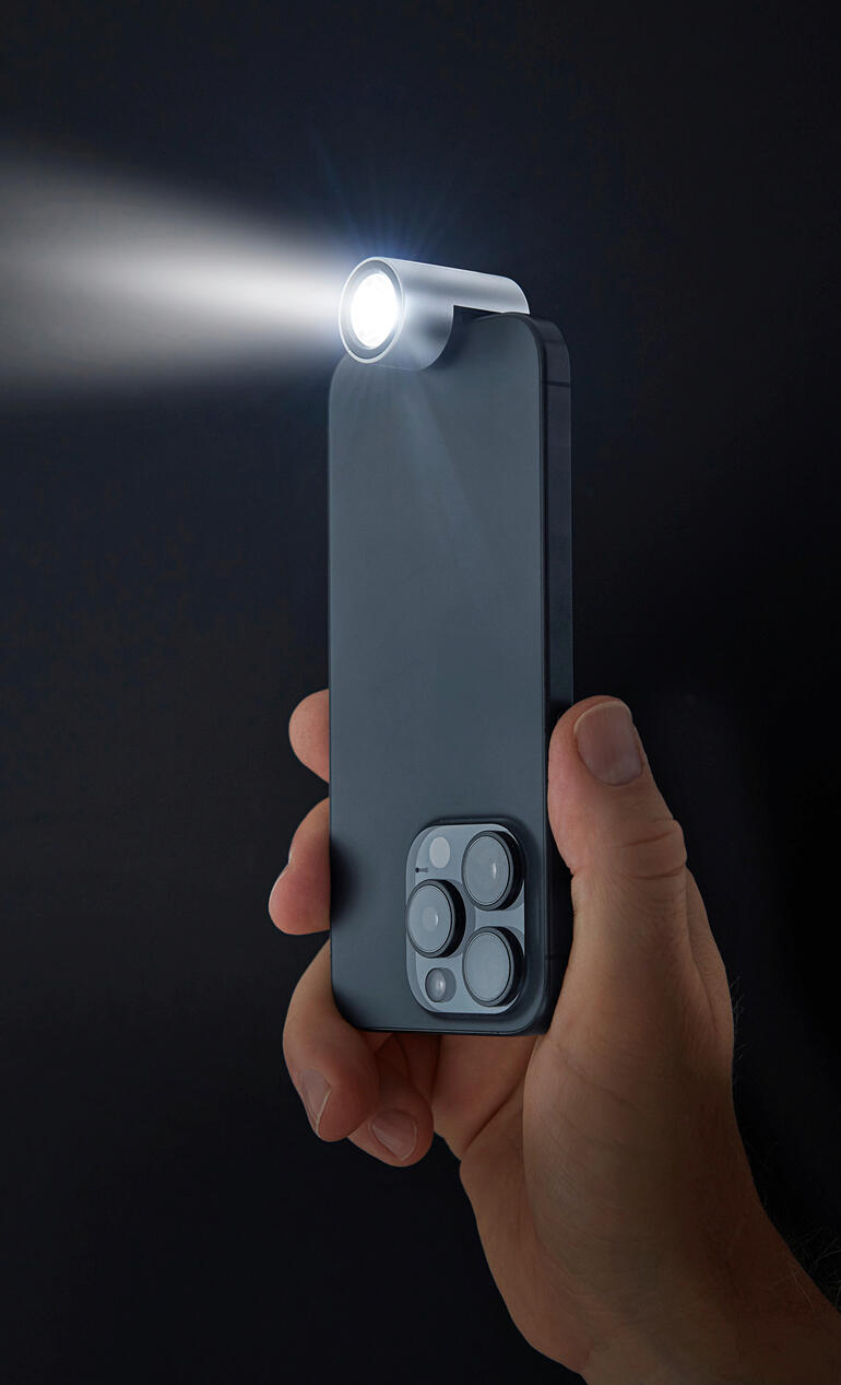 Hand gehaltene Smartphone-Taschenlampe leuchtet in dunklem Hintergrund