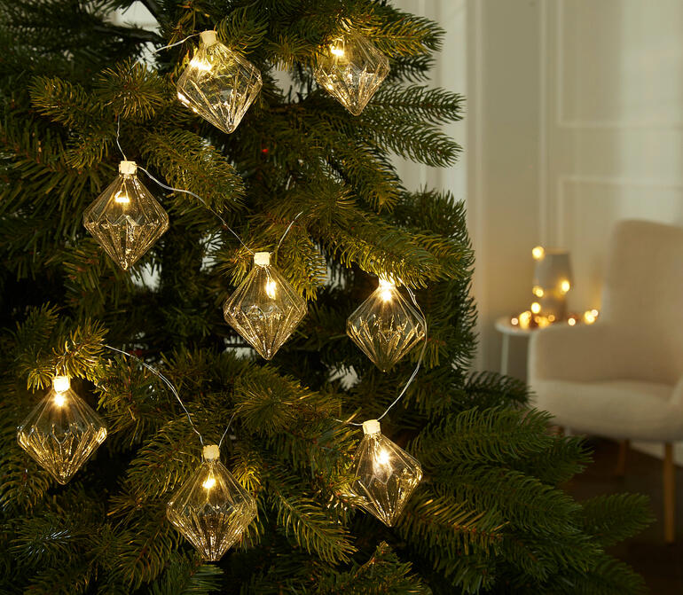 Lichterkette mit gläsernen Ornamenten am Weihnachtsbaum.