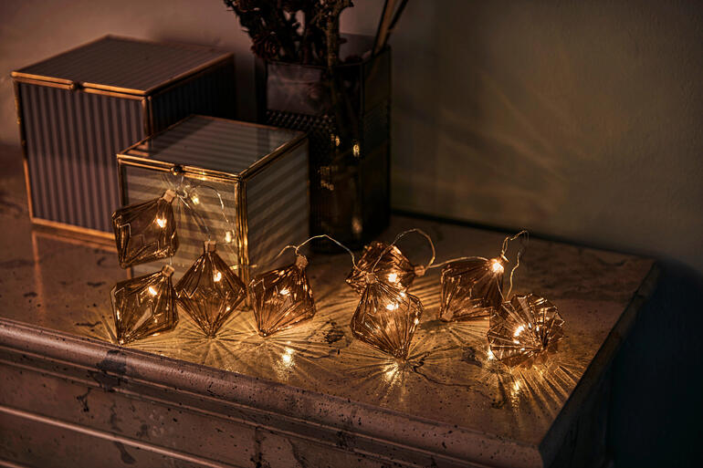 Glasornament-Lichterkette mit braunen Rauten auf einem Tisch.