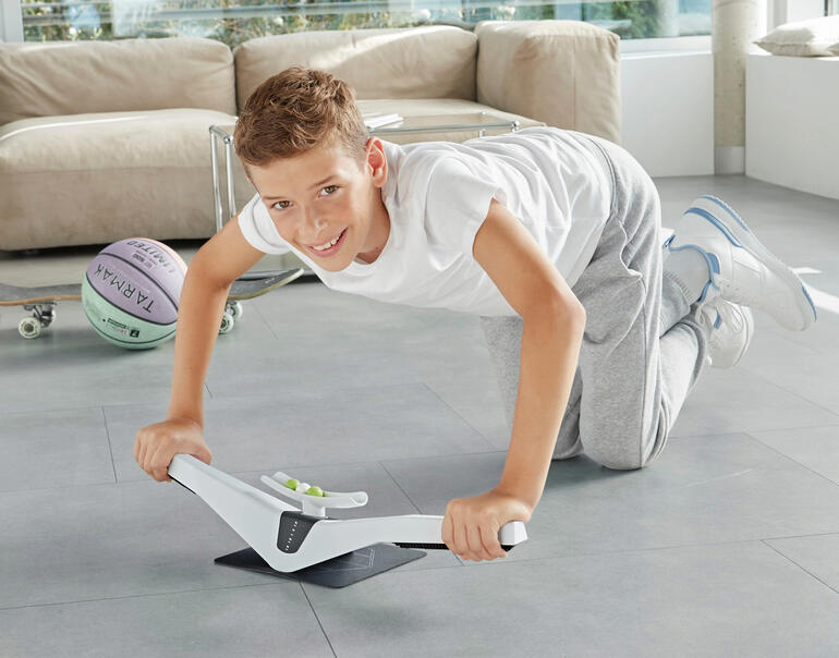 Junge übt auf dem Praep® Plank-Trainer in einem modernen Raum.