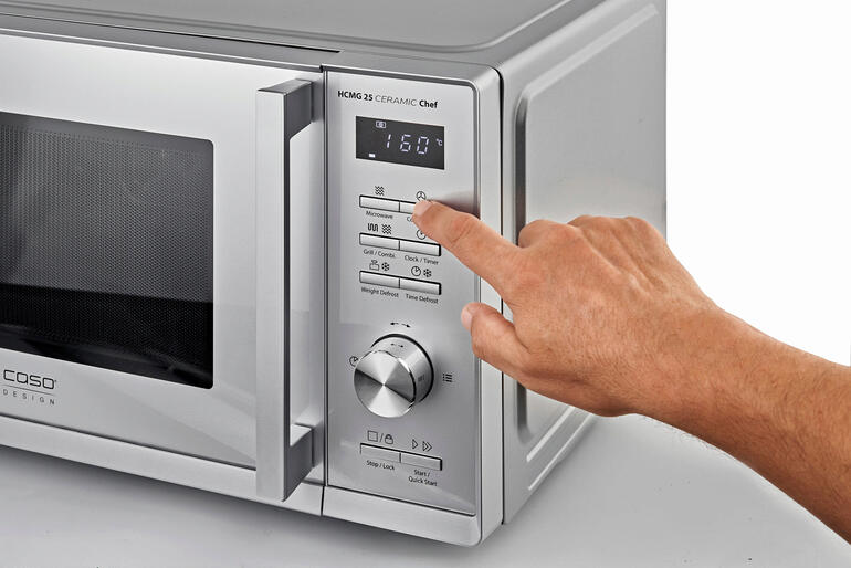 Einfach per Tastentipp wählen Sie Ihr gewünschtes Garprogramm – und die intelligente Automatik erledigt die Zubereitung perfekt. Hand drückt auf das Bedienfeld einer 3-in-1-Mikrowelle.