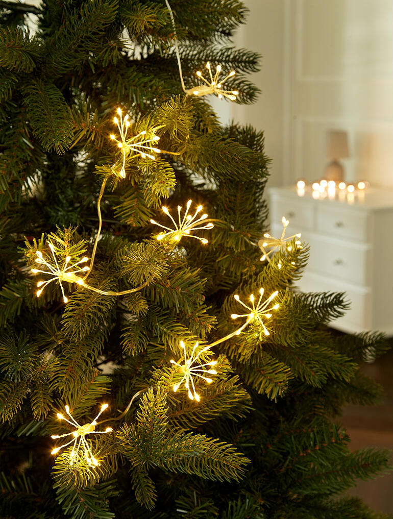 Lichterkette mit goldenen Lichtern, die wie Wunderkerzen auf einem Weihnachtsbaum wirken.
