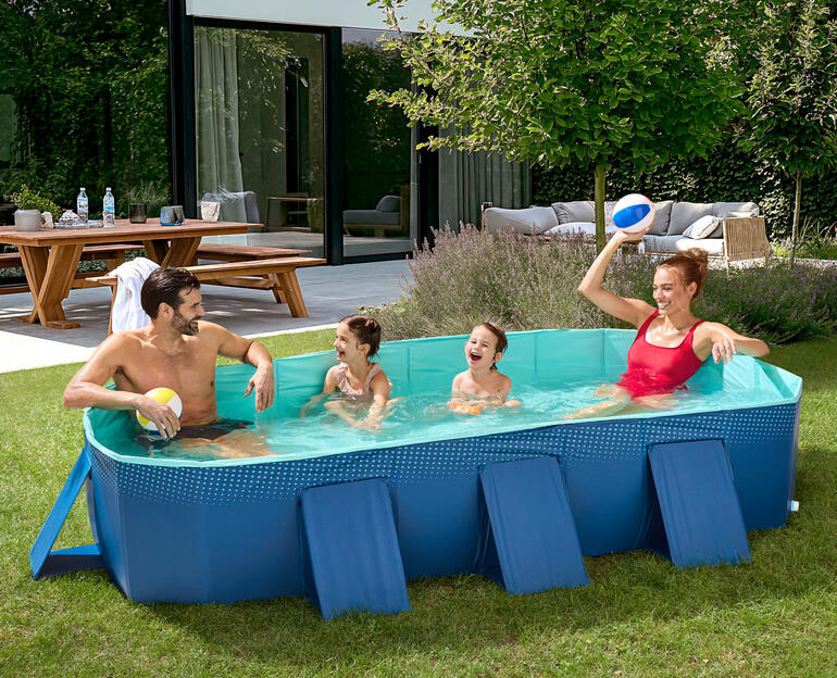 Familie im Falt-Pool im Garten mit Spielbällen.