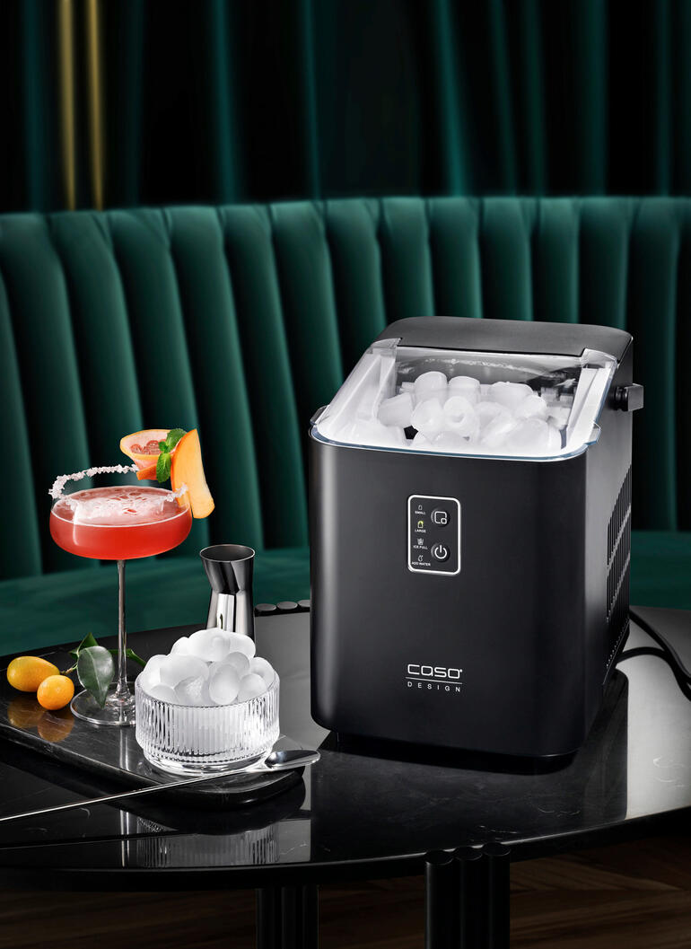 Design-Eiswürfelbereiter auf einem Tisch mit Cocktails und Eiswürfeln.