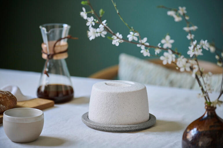 Keramik-Butterkühler auf einem Tisch mit Blumen und Kaffeekanne.