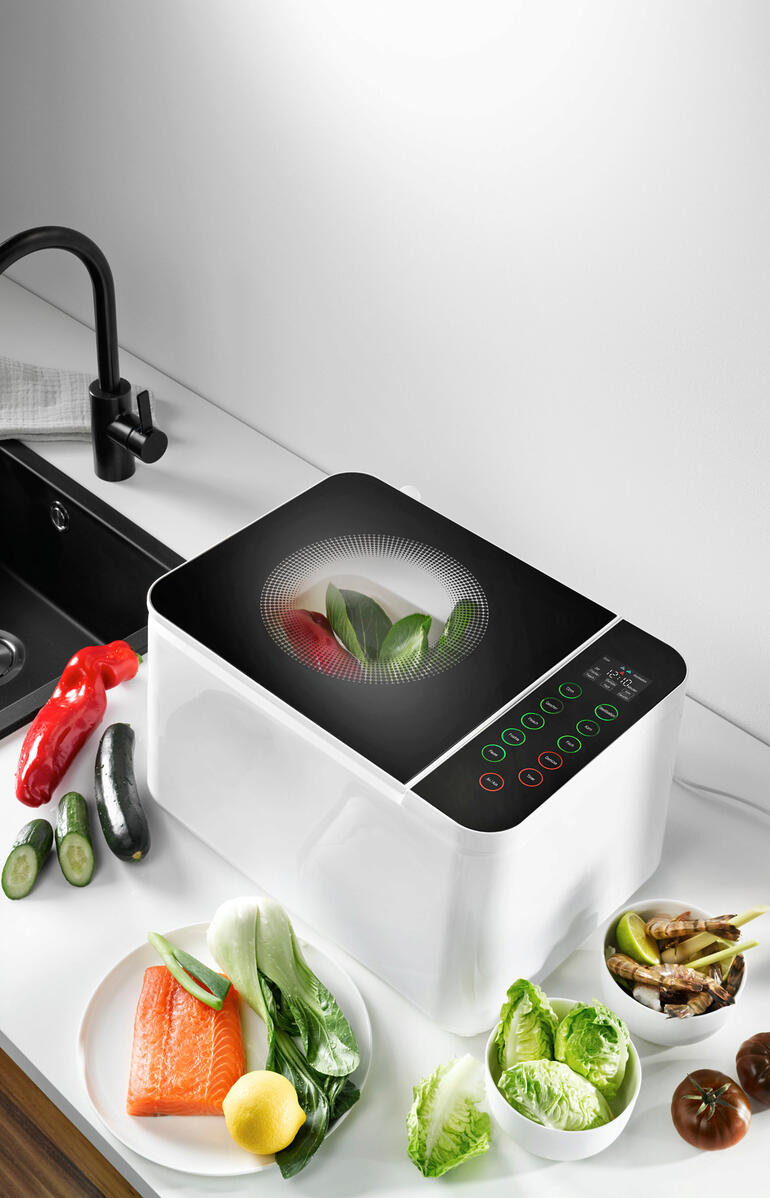 Food Washer Gerät auf Arbeitsplatte, umgeben von frischem Gemüse.