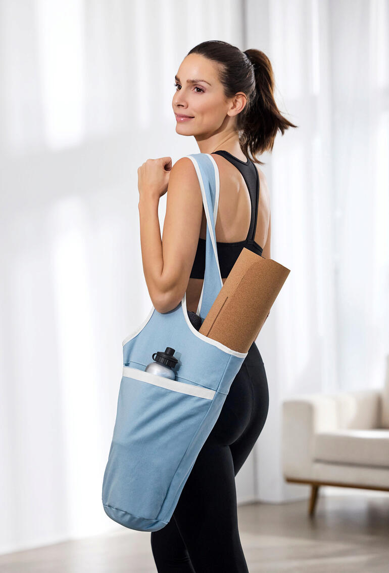 Frau trägt Yogatasche mit Gymnastikmatte und Wasserflasche.