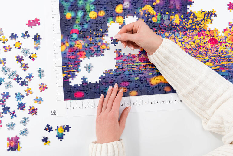 Person, die an einem bunten Puzzle arbeitet.
