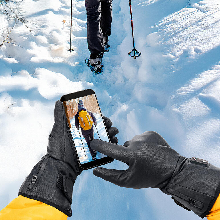 Hand mit Smartphone, die den Benutzer im verschneiten Gelände zeigt.