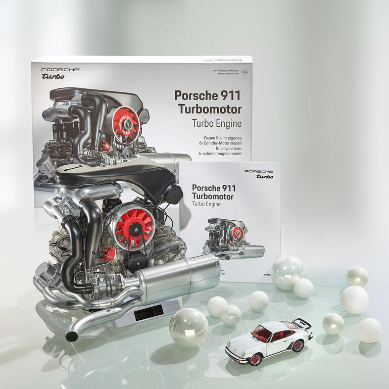 Modellset des Porsche 911 Turbo Motors mit einem kleinen Spielzeugauto auf dem Tisch.