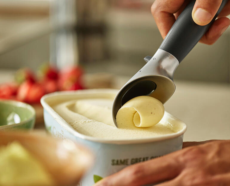 Dringt mühelos auch durch hart gefrorenes Eis und Sorbet. Hand, die Eis mit einem Portionierer aus einem Behälter mit Eiscreme entnimmt.