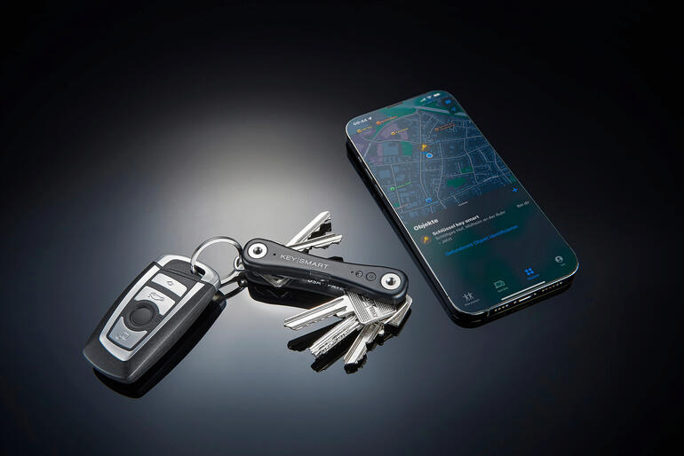 Une fois votre KeySmart® iPro localisé, vous verrez sa position dans l’application « Localiser mon » sur votre iPhone. Smarter Schlüssel-Organizer neben einem Schlüsselbund und einem Smartphone auf einem Tisch.