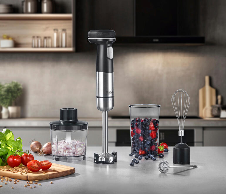 Kabelloses Stabmixer-Set mit Mixer, Rührbesen, und Behälter auf einer Küchentheke.