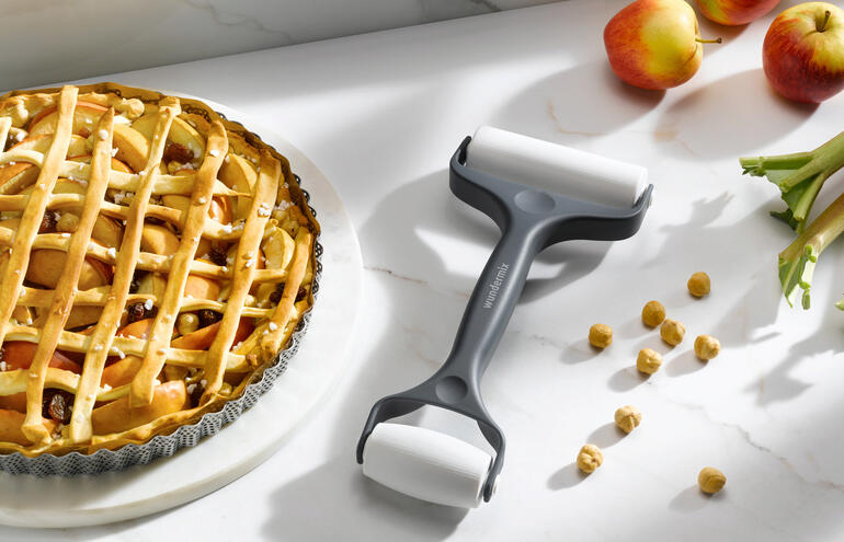 Doppel-Teigroller steht neben einem Apfelkuchen auf einem Küchentisch.