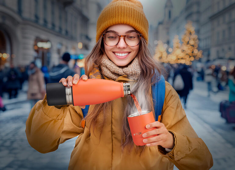 Frau auf der Straße gießt aus einer Isolierflasche in einen Becher.