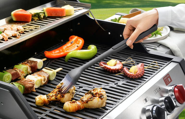 Grillpinsel in Aktion, um Fleisch auf dem Grill aufzutragen.