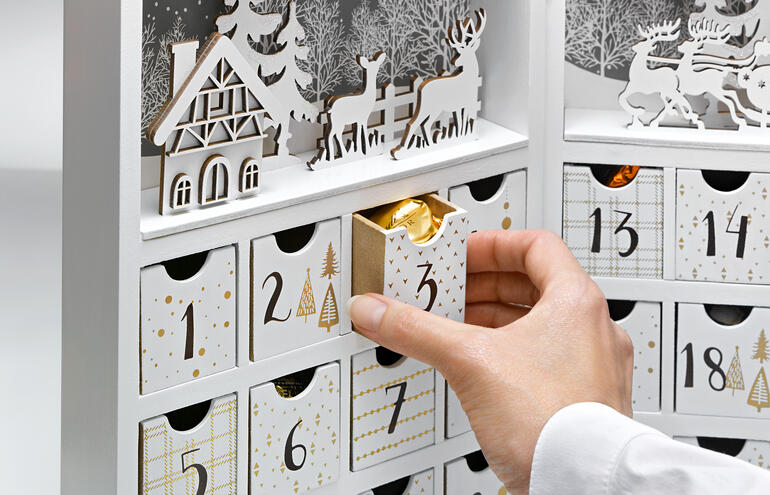 Adventskalender mit einem Winterdorf-Design und geöffnetem Türchen.