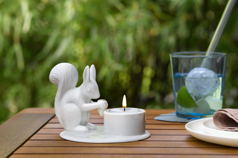 Ohne Windspiel perfekt auch im Sommer auf dem Gartentisch. Teelichtkarussell mit Eichhörnchen auf einem Tisch im Freien, mit Getränken und Geschirr.