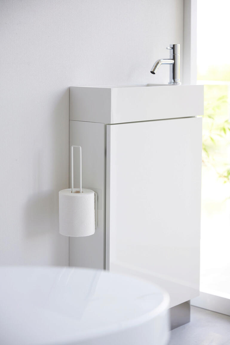 Weißer Design WC-Rollenhalter an einem modernen Badezimmermöbel angebracht.