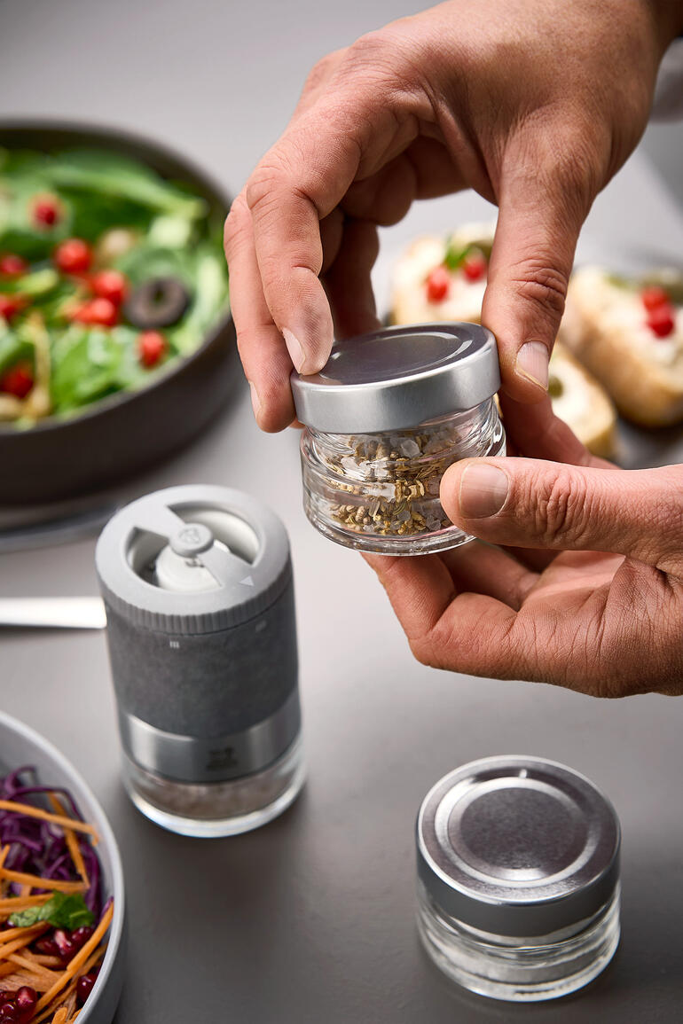 Peugeot Zirkonia-Salzmühlen-Set, Hände halten eine Gewürzdose über einer Salatschüssel