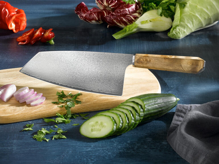 Damast Nakiri-Messer auf einem Holzbrett, umgeben von frischen Gemüse.