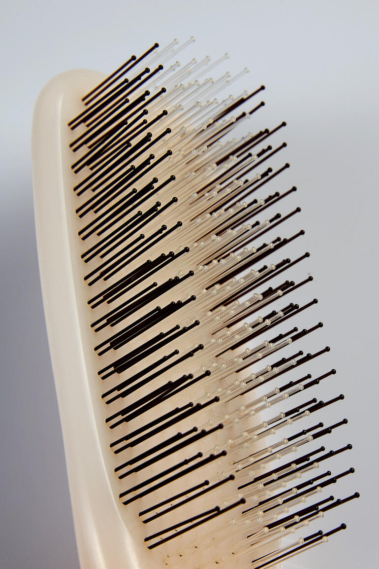 Nahaufnahme einer Haarbürste mit Schutzstiften auf weißem Hintergrund.