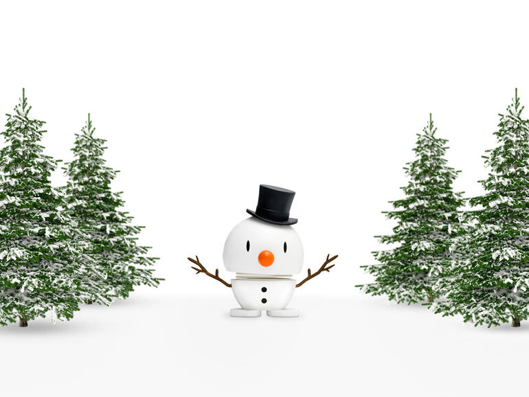 Fröhliche Festtage – mit den putzmunteren Hoptimisten in Weihnachtsstimmung. Hoptimist Schneemann mit Zylinder zwischen schneebedeckten Bäumen.