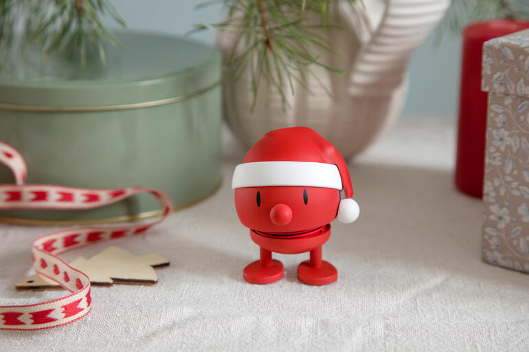 Hoptimist Schneemann mit rotem Weihnachtsmütze auf festlichem Tisch.