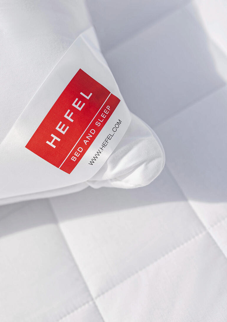 Nahaufnahme eines weißen Kissens mit einem roten Hefel-Logo.