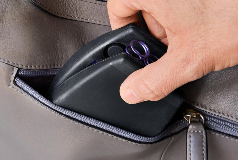 Hand greift Kompakt-Oberkörpertrainer aus einer Tasche