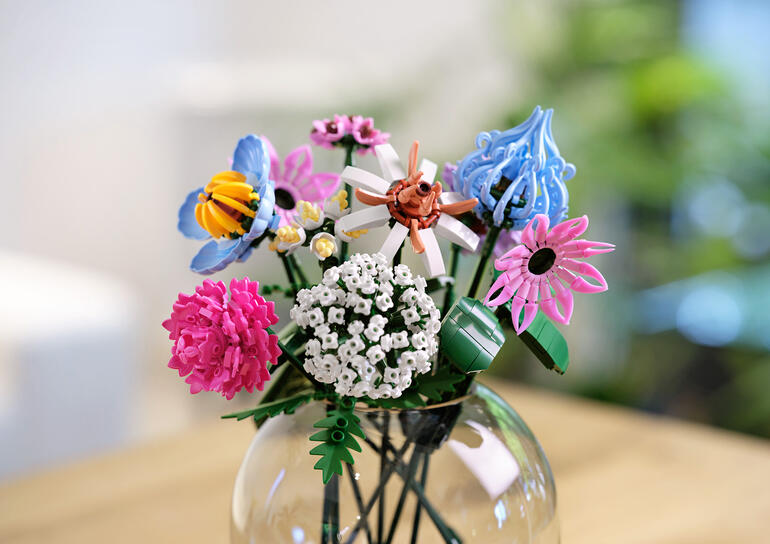 Blumenstrauß aus Klemmbausteinen in Rosé- und Lilatönen in einer Vase.
